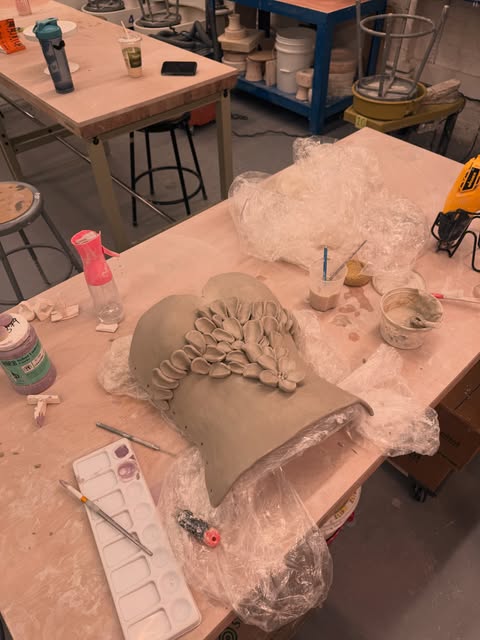 Sculpted clay corset with pleated shell details on a studio table