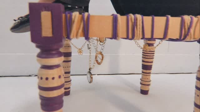 The finished khatli wrapped in yarn with jewelry chains draped from it